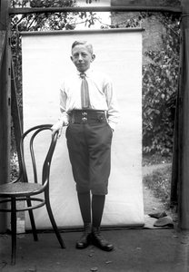 853686 Portret van een onbekende jongen, leunend op een stoel.